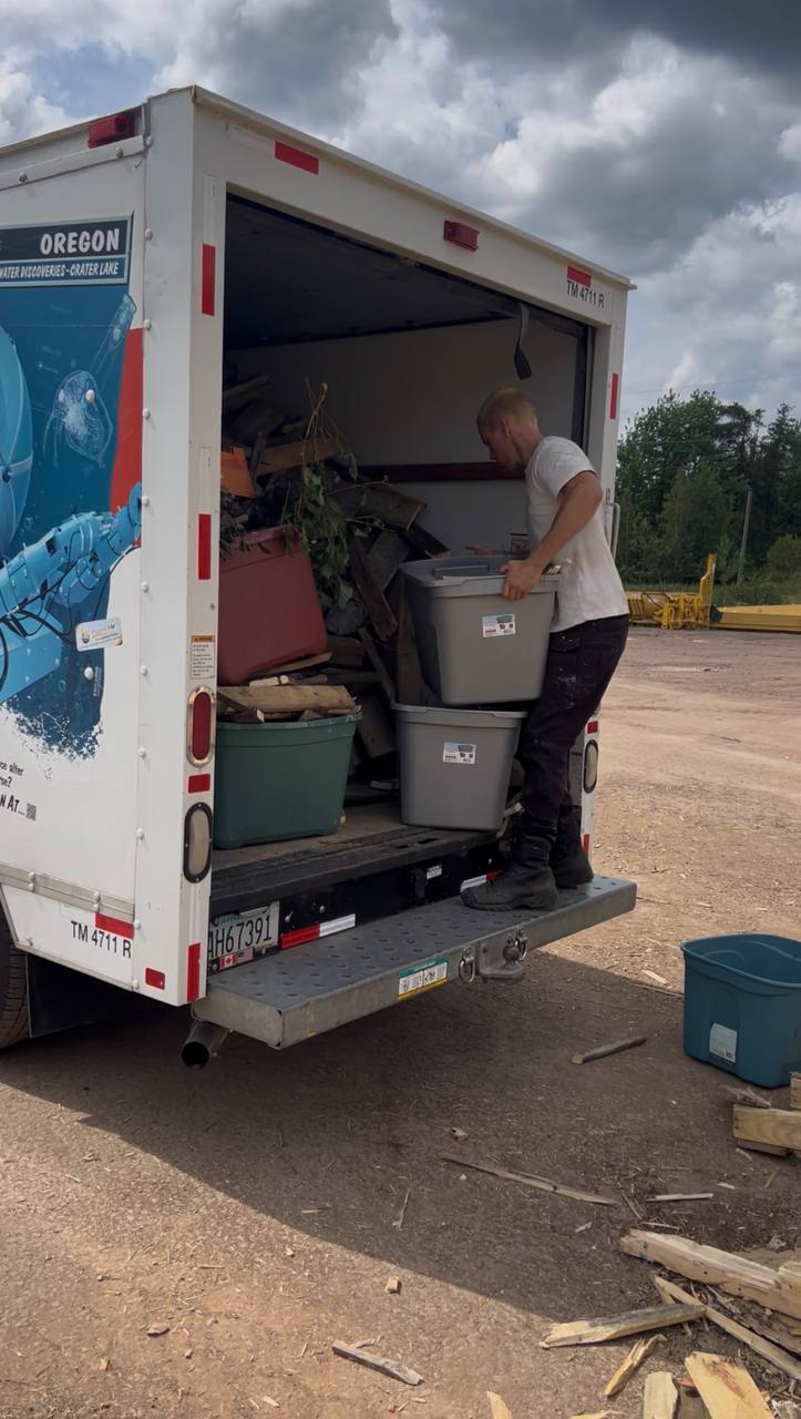 Worker lifting bins into the junk removal truck at a job site